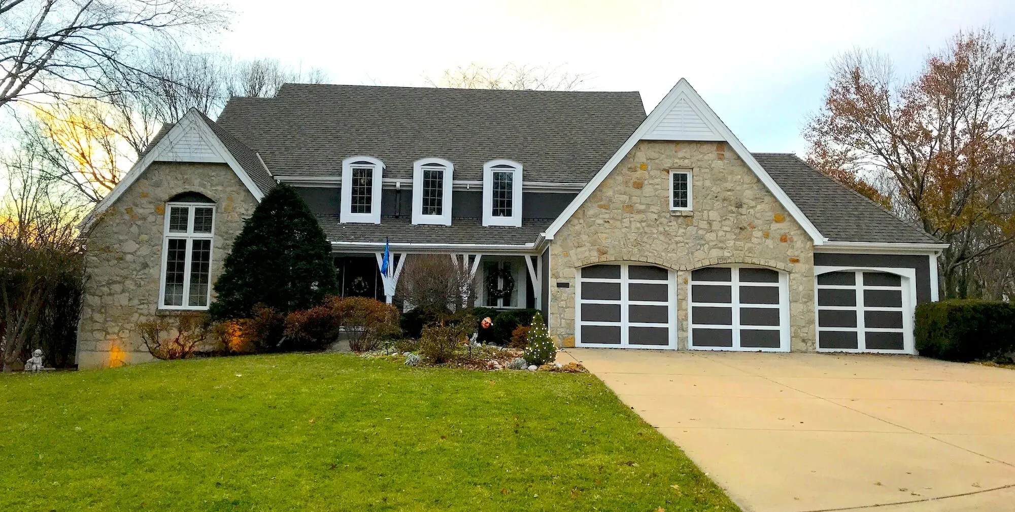 Two-story Kansas City area home with stone gables, dark siding, and white trim