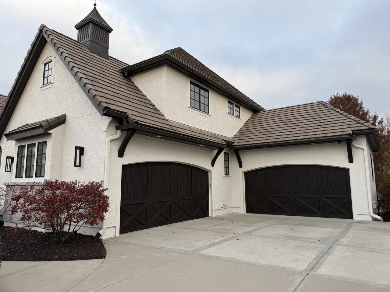 White stucco home with dark-stained garage doors painted by Catalyst Painting