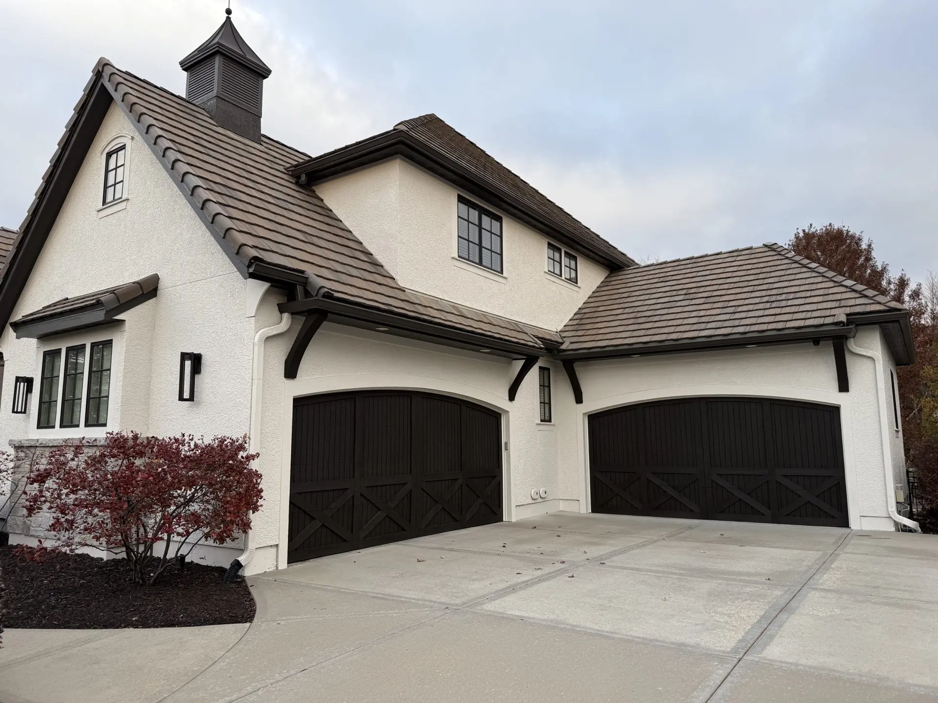 White stucco home with dark garage doors painted by Catalyst Painting